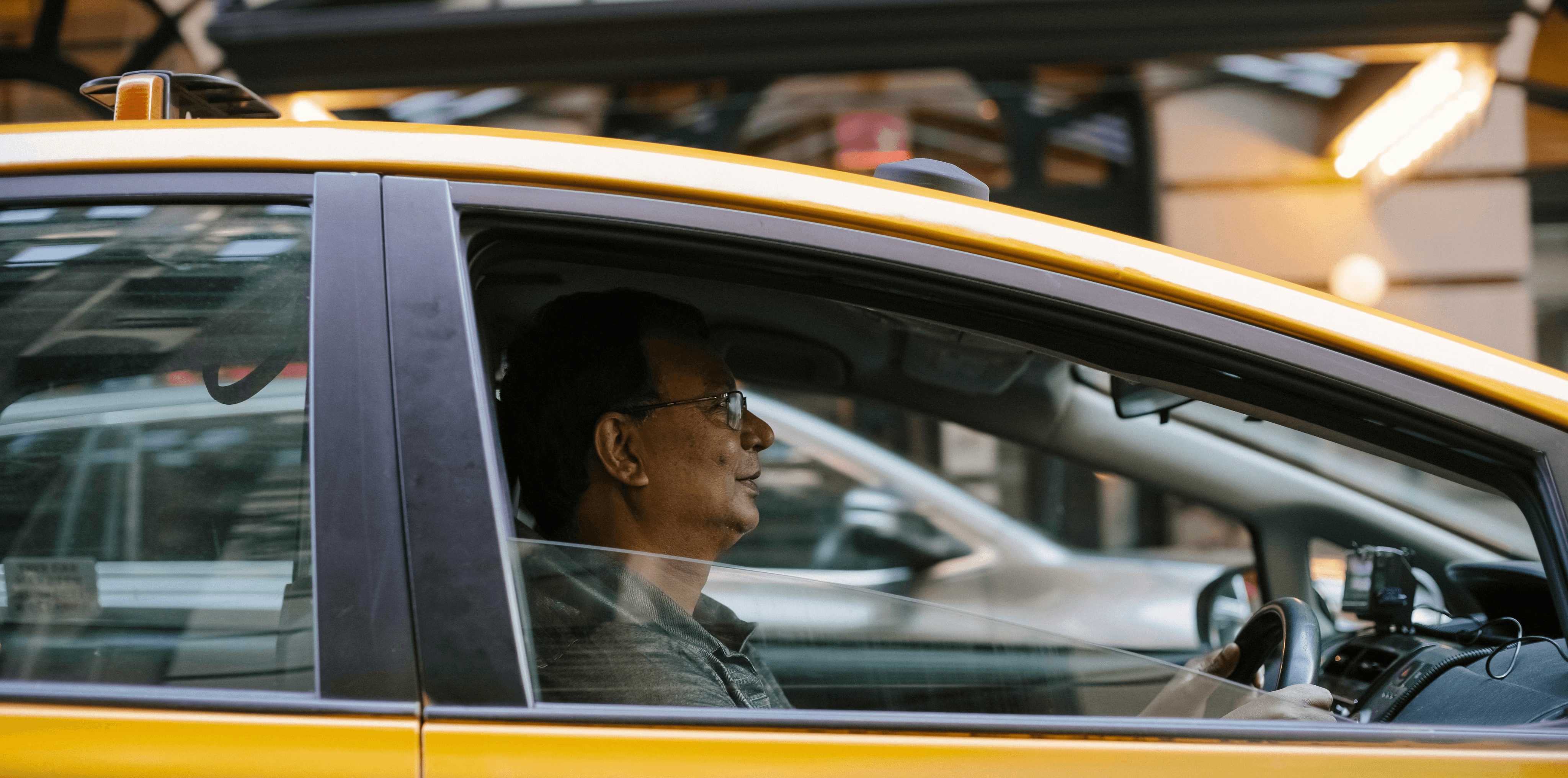 Man driving a yellow taxi cab.