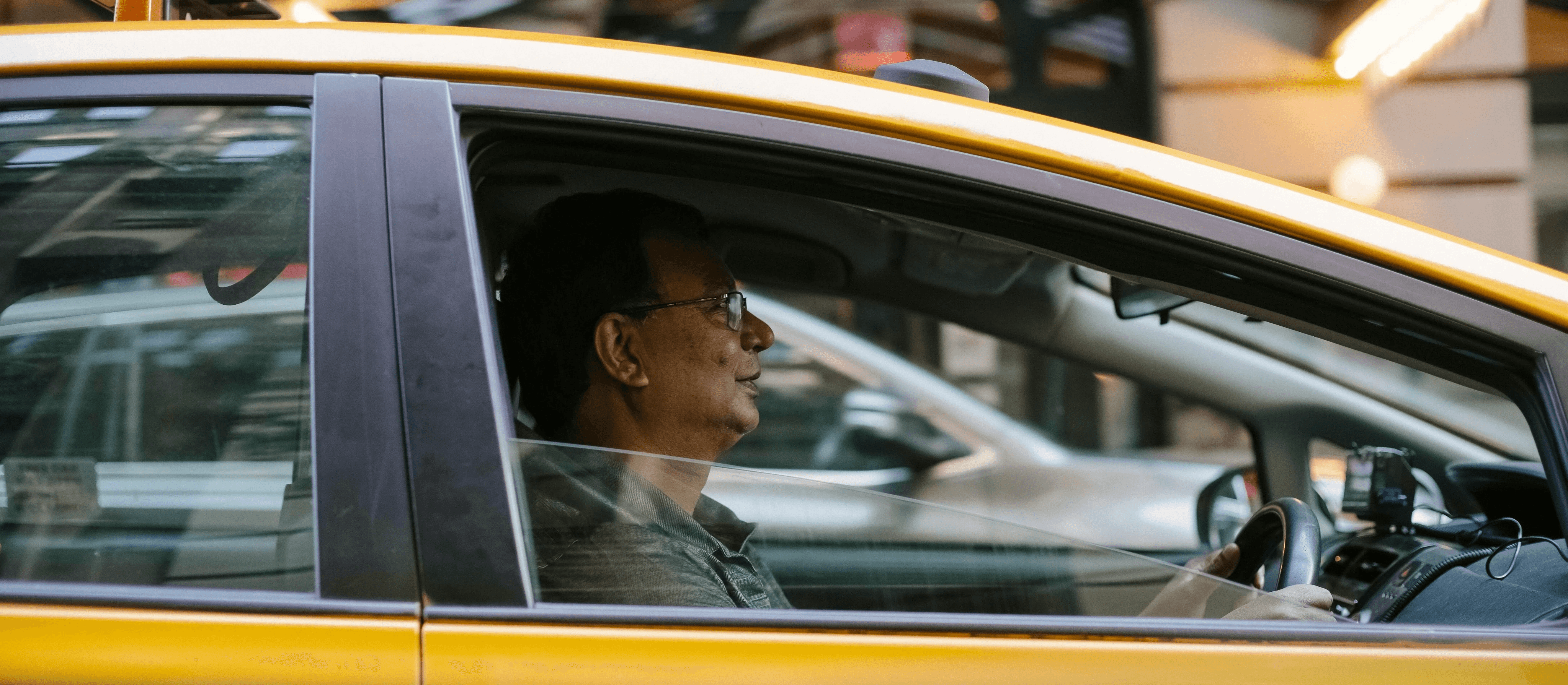 Man driving a yellow taxi cab.